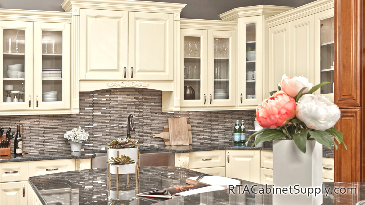 Holmdel Cream kitchen full view with an island, a sink, glass door cabinets, wall and base cabinets.