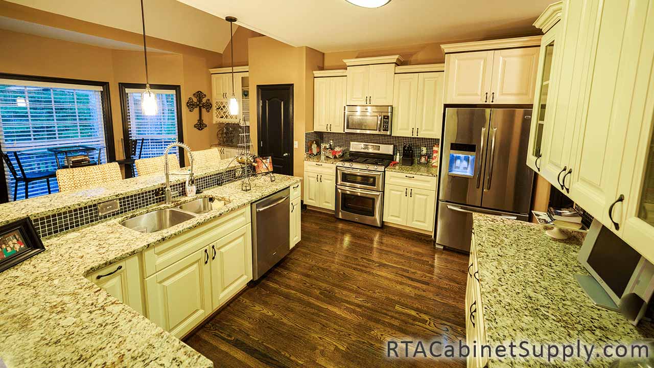 Oxfrord Cream kitchen full view with an island, lighting, a fridge, wall and base cabinets.