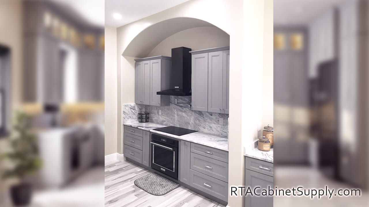 Preston Grey kitchen angle view with a range hood, a countertop, wall and base cabinets.