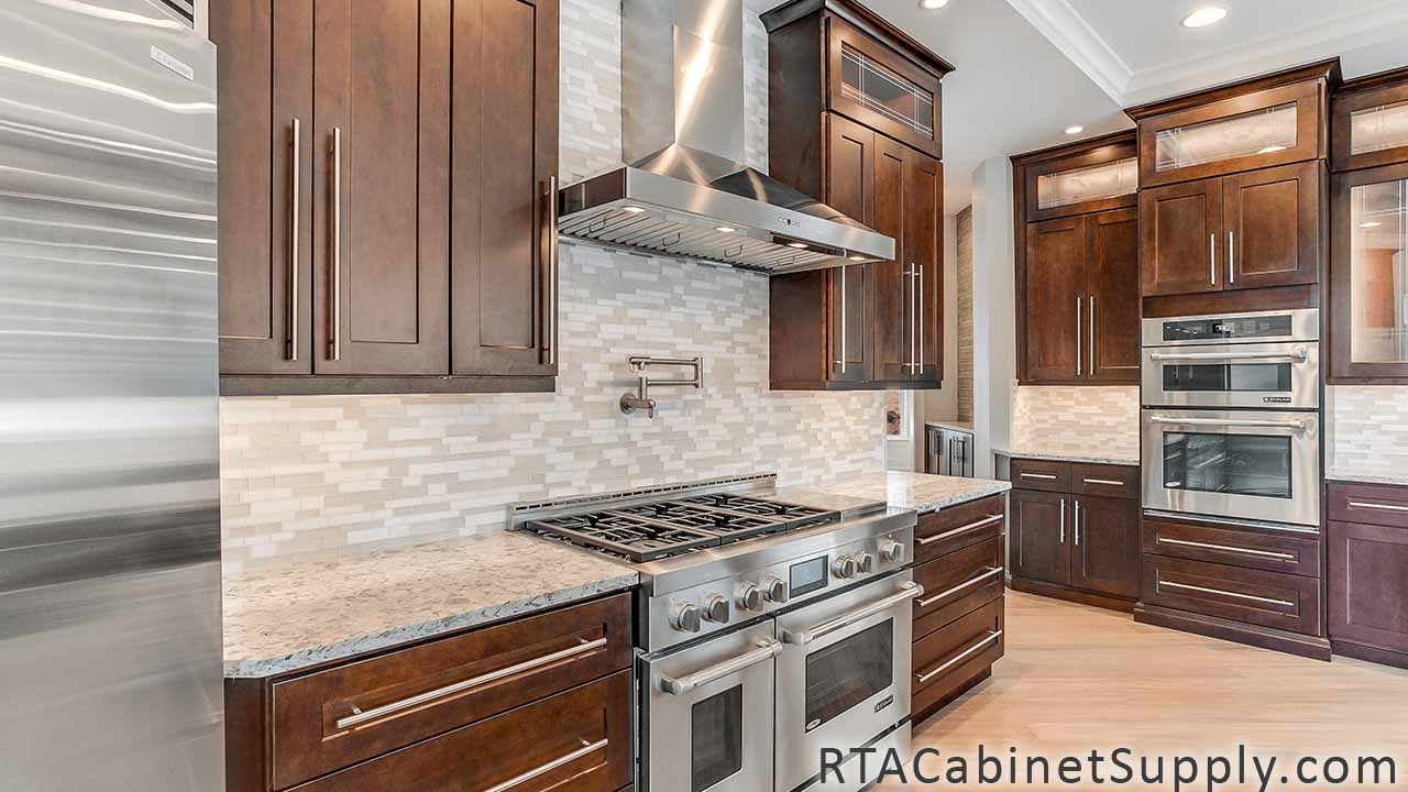 Sienna Shaker kitchen angle view with a range hood, an oven, a countertop, wall and base cabinets.