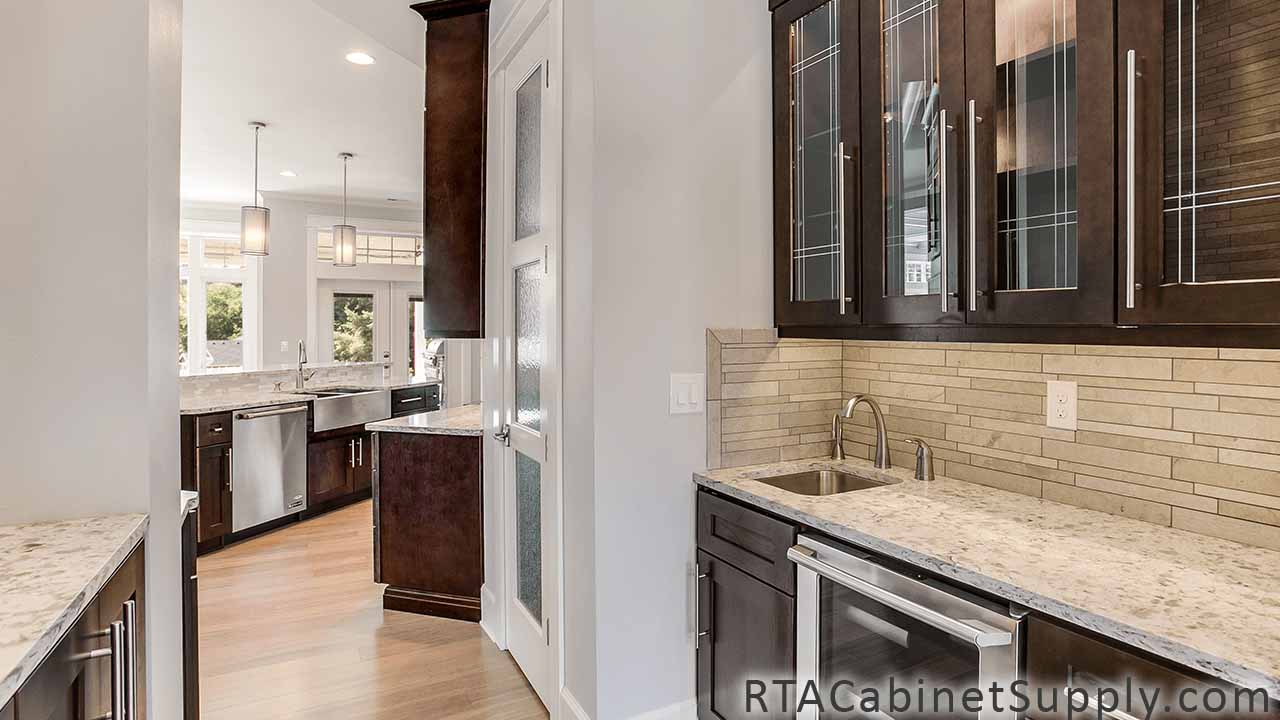 Sienna Shaker kitchen angle view with glass door cabinets, a countertop, an island, wall and base cabinets.