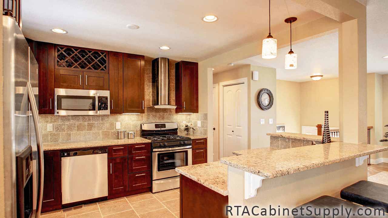 Sienna Shaker kitchen full angle view with a wine rack cabinet, a range hood, lighting, an oven, a countertop, an island, wall and base cabinets.