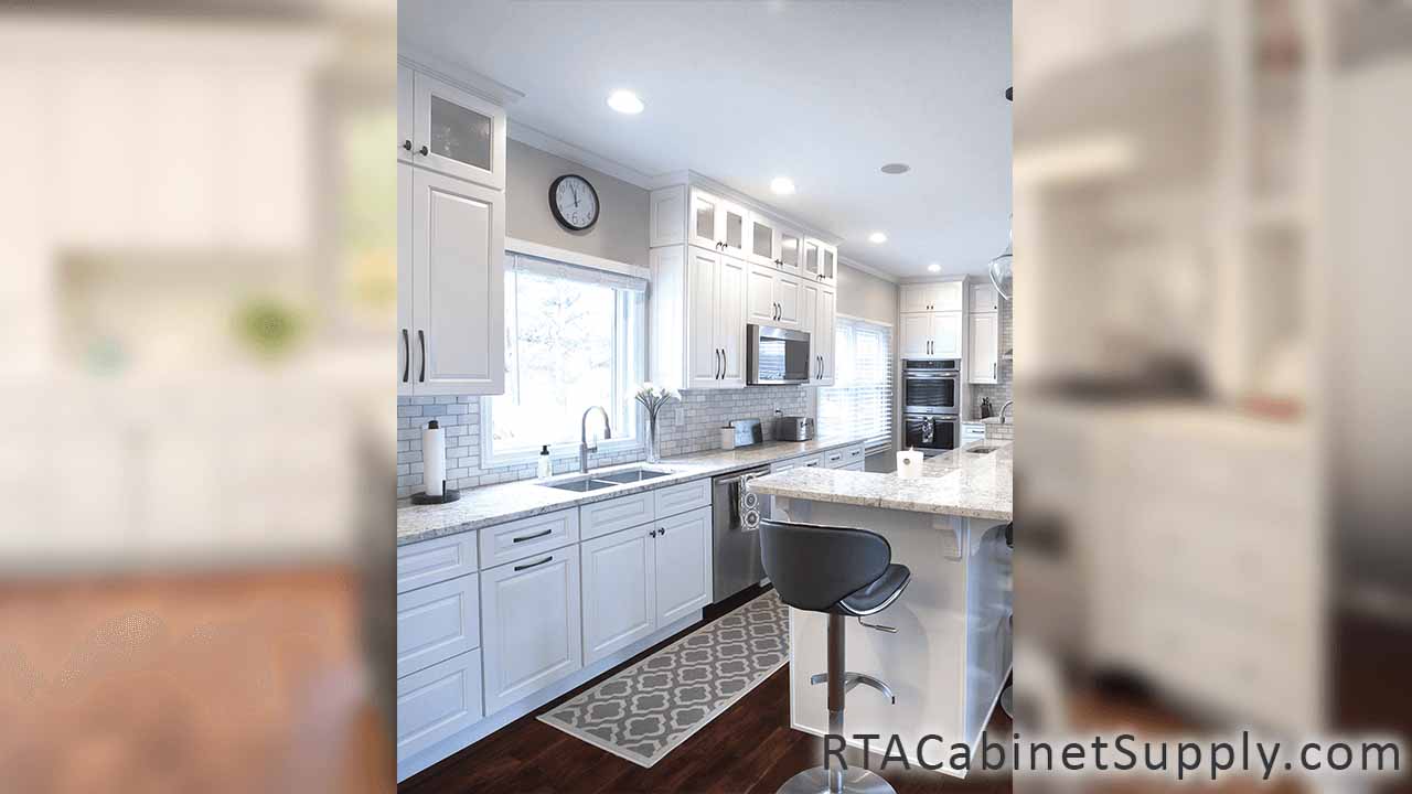 Verona White kitchen angle view with an island, a countertop, glass door cabinets, wall and base cabinets.