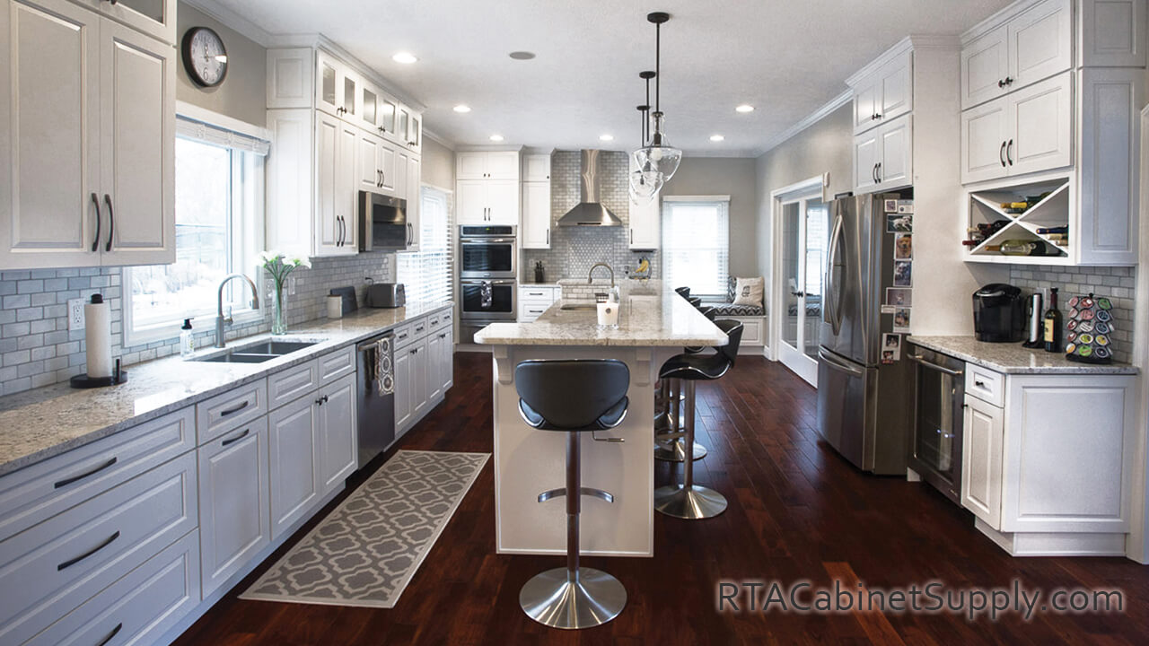 Verona White kitchen full view with a range hood, lighting, a wine rack cabinet, an island, a countertop, wall and base cabinets.