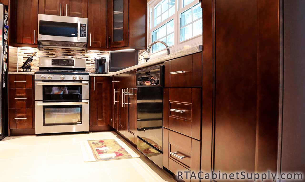 Walnut Shaker kitchen close up view with an oven, a glass door cabinet, a countertop, wall and base cabinets.