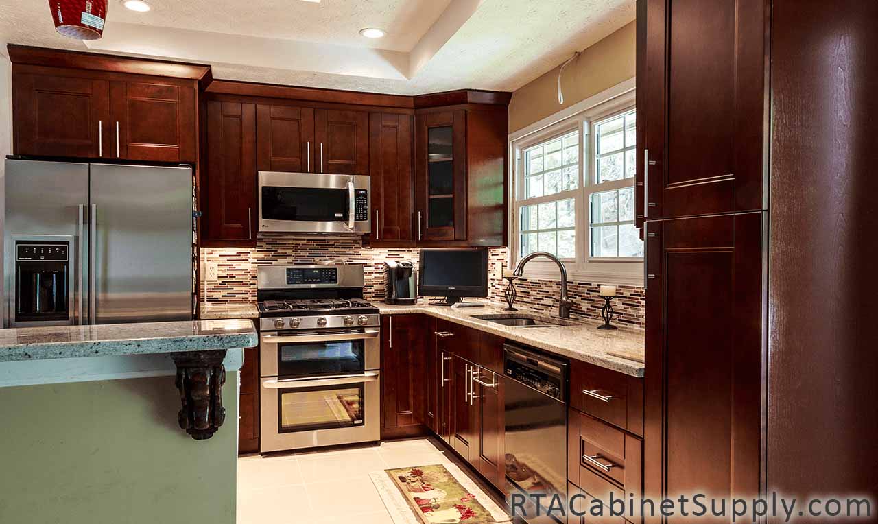 Walnut Shaker kitchen full view with a fridge, a glass door cabinet, an island, a countertop, lighting, wall and base cabinets.