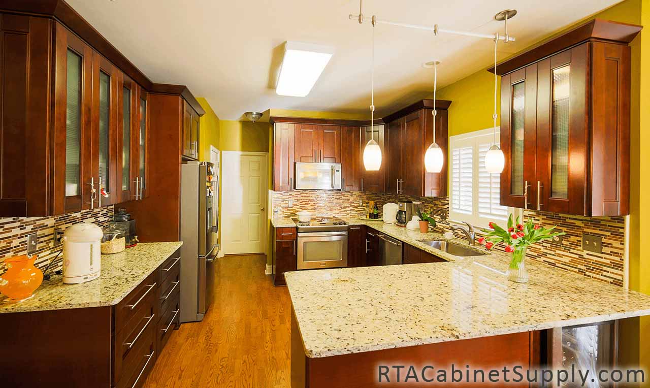 Walnut Shaker kitchen full view with an oven, glass door cabinets, a countertop, lighting, wall and base cabinets.