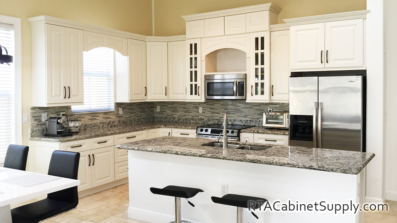 Windsor Ivory kitchen angle view with a range hood cover, a fridge, an island, a countertop, wall and base cabinets.