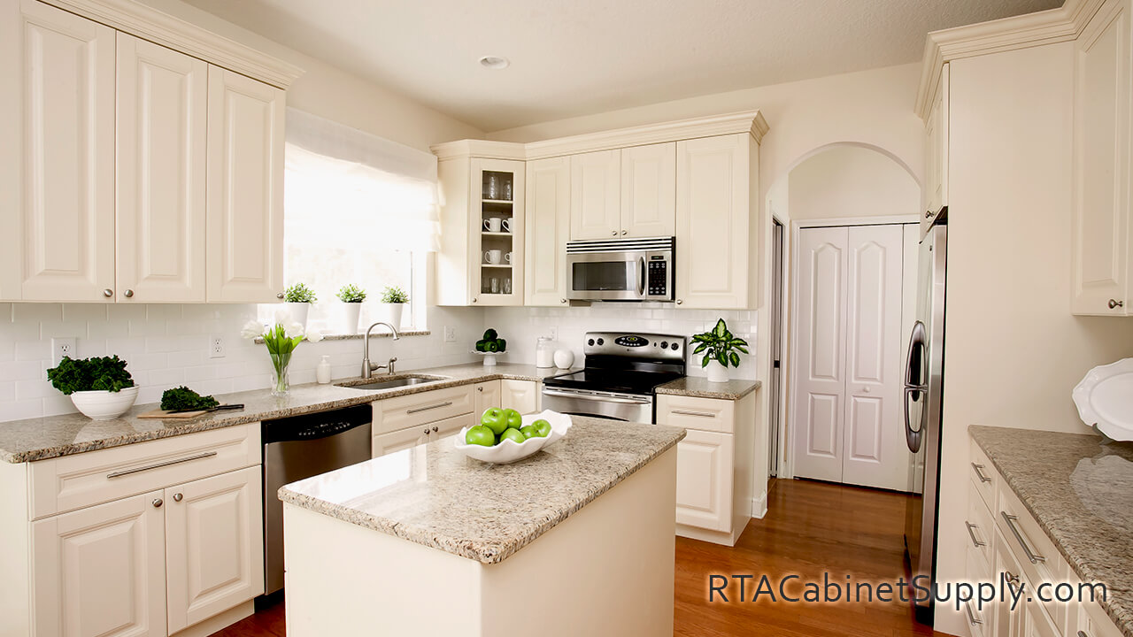 Holmdel Cream kitchen full angle view with an island, wall and base cabinets, glass door cabinets and a fridge.