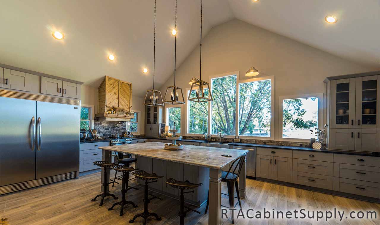Anchester Grey kitchen full view with lighting, an island, a fridge, glass door cabinets, wall and base cabinets.