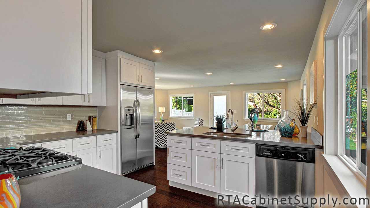 Classic White Shaker kitchen close up angle view with an island, wall and base cabinets and a fridge.