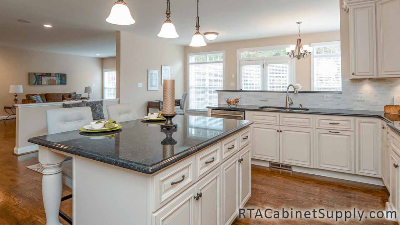 Country Cream kitchen angle view with an island, wall and base cabinets, and lighting.