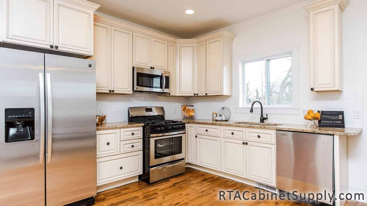 Country Cream kitchen angle view with a fridge, lighting, wall and base cabinets.
