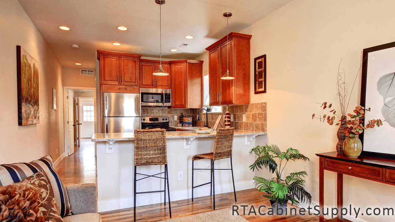 Coventry Toffee Glaze kitchen angle view with chairs, a countertop, wall cabinets and a fridge.