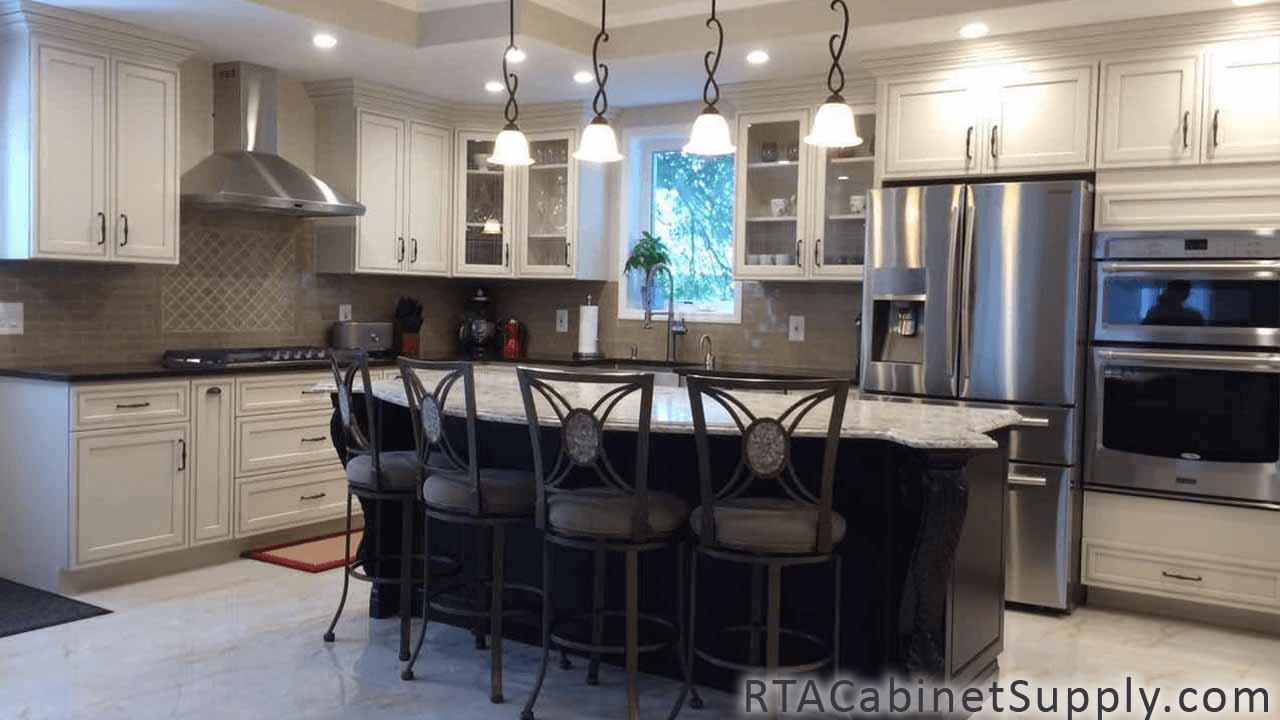 Dark Cream Glaze kitchen full view with an island, chairs, lighting, a range hood, glass door cabinets, wall and base cabinets.