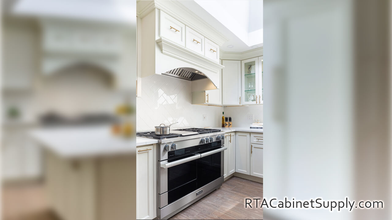 Hanover Dove kitchen close up angle view with a range hood cover, an oven, wall and base cabinets.