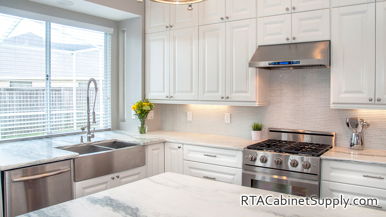 Essex White kitchen angle view with a countertop, a range hood, an oven, wall and base cabinets.