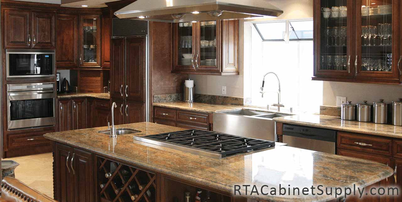 Jackson Chocolate kitchen angle view with an island, a wine rack cabinet, a range hood, glass door cabinets, wall and base cabinets.
