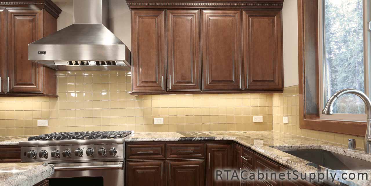 Jackson Chocolate kitchen close up view with a countertop, a range hood, an oven, wall and base cabinets.
