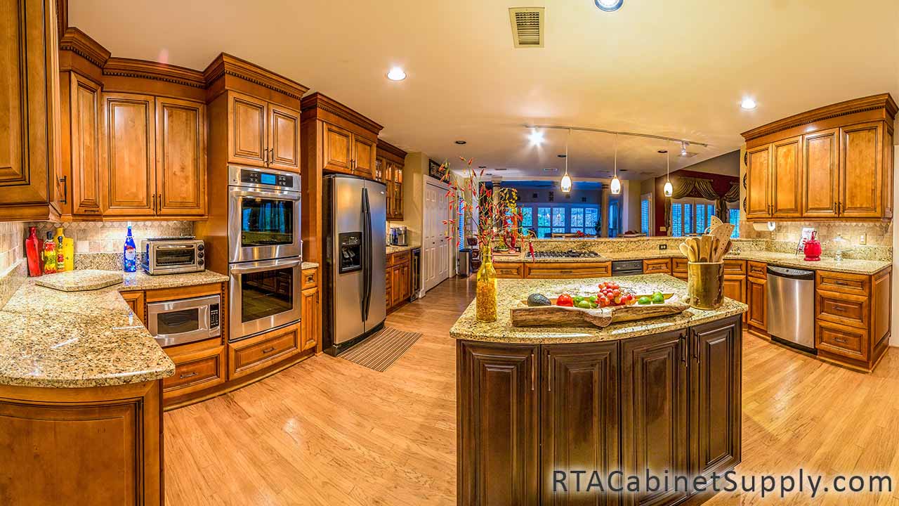 Kingston Maple kitchen full view with an island, lighting, a countertop, a fridge, wall and base cabinets.