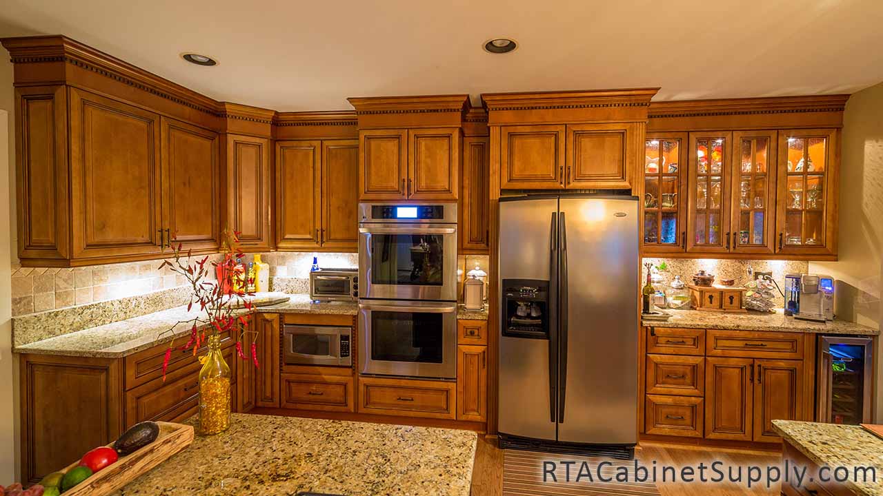 Kingston Maple kitchen full view with a fridge, glass door cabinets, a countertop, wall and base cabinets.