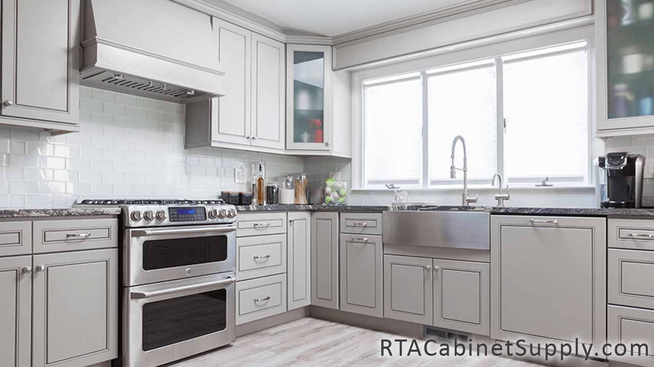 Modern Grey kitchen angle view with an oven, a range hood, a farmhouse sink cabinet, wall and base cabinets.