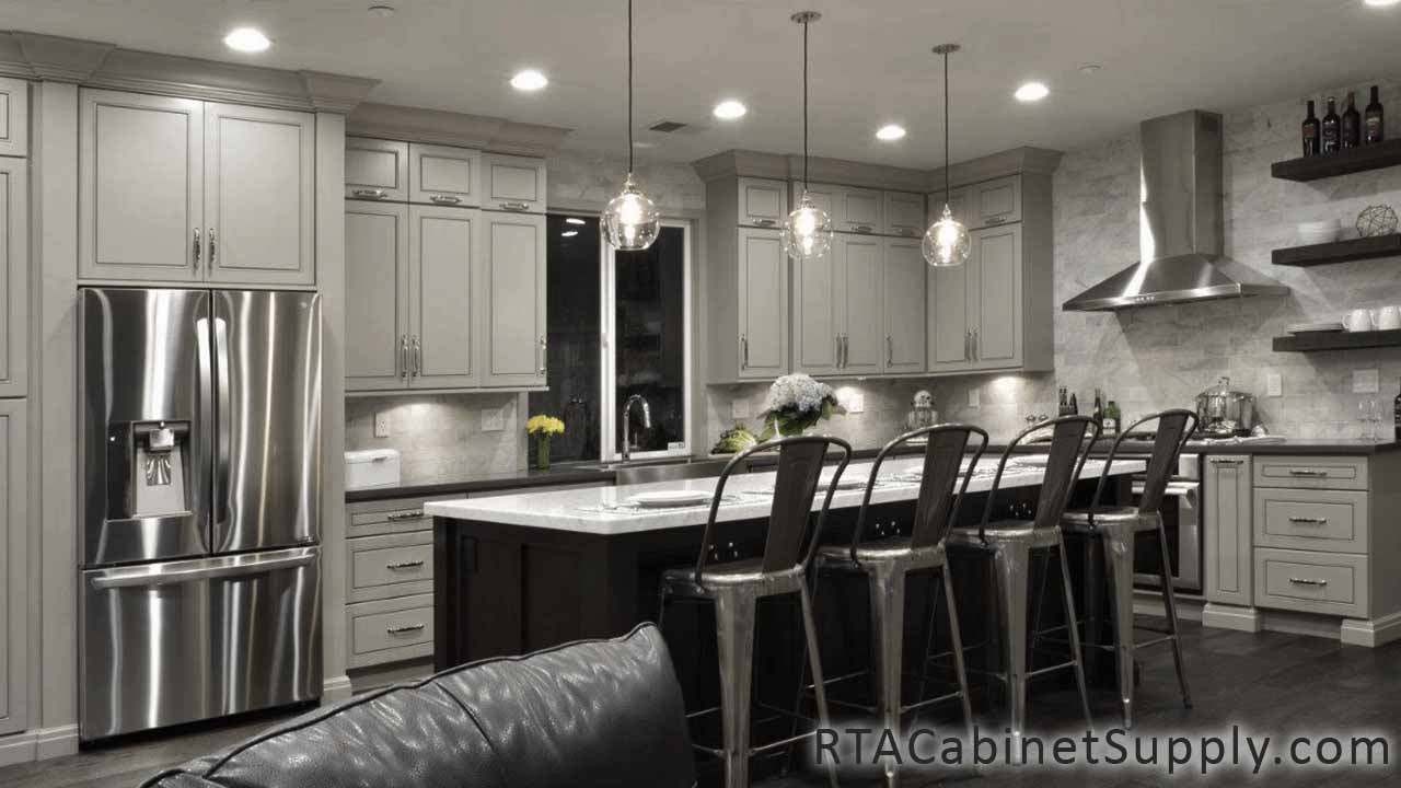 Modern Grey kitchen angle view with an island, lighting, a fridge, wall and base cabinets.