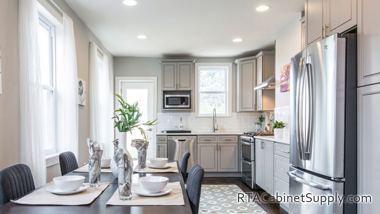 Modern Grey kitchen close up view with a table, a fridge, wall and base cabinets.